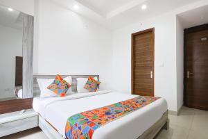a bedroom with a large white bed with colorful pillows at FabHotel Neu-Nest in Rishīkesh