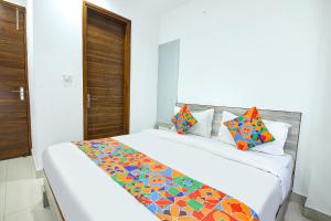 a bedroom with a large white bed with colorful pillows at FabHotel Neu-Nest in Rishīkesh