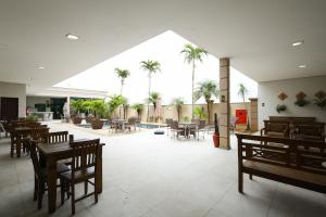 a restaurant with wooden tables and chairs and palm trees at Class Hotel Pouso Alegre in Pouso Alegre