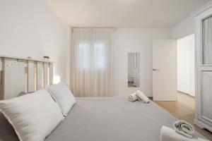 a white bedroom with a large bed with white pillows at Apartament Platja L'arquitecte in L'Ampolla