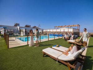 a group of people sitting on lounge chairs next to a pool at Hotel Boutique Rosario Martin in Puerto del Rosario