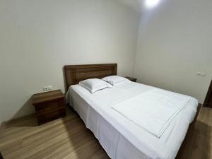 a bedroom with a white bed and a wooden floor at Dadiani Apartment in Tbilisi City