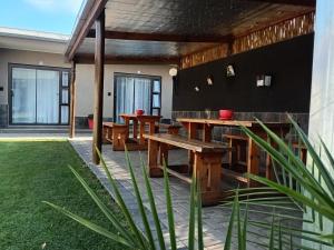a patio with wooden benches and tables in a house at Andante Guesthouse Klerksdorp in Klerksdorp