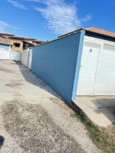 a blue building with a white garage door at Casa com Piscina Privativa e Área Gourmet in Rio das Ostras