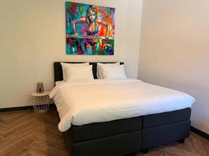 a bed in a room with a painting on the wall at Stylish Studio with Balcony, Near Tilburg Station in Tilburg