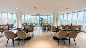 a dining room with tables and chairs and windows at The Theme, Jaipur in Jaipur