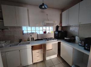 a small kitchen with white cabinets and a sink at Duplex en plein centre du village in Voreppe +5 photos