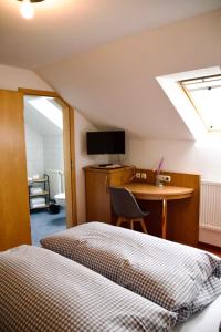 a bedroom with a bed and a desk with a television at Hotel Restaurant Ampertal in Haag an der Amper