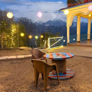 a table and chairs with a view of a mountain at Tree house munsyari in Munsyari
