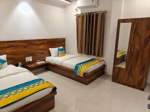 a hotel room with two beds and a mirror at Hotel Parineeta in Khagaria