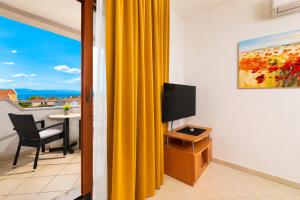 a living room with a tv and a yellow curtain at Apartments Kvarner 2 in Malinska