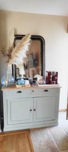 a white dresser with a mirror on a wall at Les Jardins de la Pinellerie in Vue