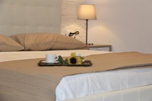 ジャルディーニ・ナクソスにあるFederico's Homeのベッドの上にコーヒーカップと花を用意したトレイ