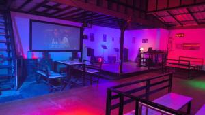 a room with pink and purple lights and tables and a screen at บ้านสวนร่มไม้แอ๊ดเชียงดาว in Ban Hua Thung +26 photos