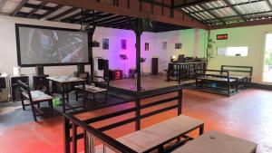 a large screen in a room with tables and chairs at บ้านสวนร่มไม้แอ๊ดเชียงดาว in Ban Hua Thung