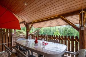 a table and chairs on a porch with a table and a window at Chalet des Charbonneux, nature in Le Ménil