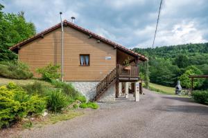 a small wooden house with a balcony on a road at Chalet des Charbonneux, nature in Le Ménil