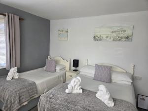 a bedroom with two beds with towel animals on them at The Elmer in Yapton