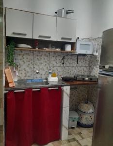 a small kitchen with a red curtain on the counter at Meu refúgio 01 in Belém