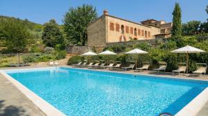 a swimming pool with chairs and umbrellas in front of a building at Tenuta Lupinari in Bucine