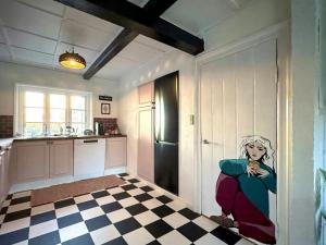 a kitchen with a painting of a woman sitting on the door at Autentisk Gård Tæt På Vandet På Samsø in Ballen