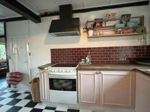 a kitchen with a white stove and a red brick wall at Autentisk Gård Tæt På Vandet På Samsø in Ballen