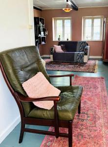 a living room with a leather chair and a couch at Autentisk Gård Tæt På Vandet På Samsø in Ballen +14 photos