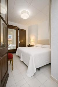 ein Schlafzimmer mit einem großen weißen Bett und einem roten Stuhl in der Unterkunft Ca La Roseta in Castellfollit de la Roca