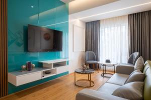 a living room with a couch and a tv on a wall at Clubway Grand A Boutique Hotel Jorhat in Jorhāt