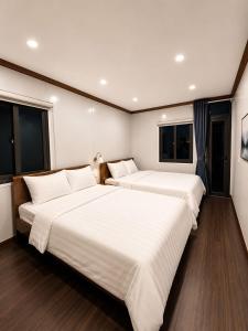two beds in a room with two windows at ILLUMI Homestay in Dong Hoi