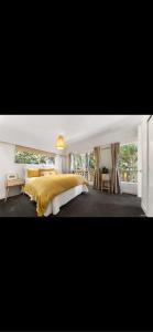 a bedroom with a yellow bed and a window at Sunbird House Piha in Piha