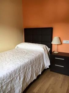 um quarto com uma cama e uma mesa com um candeeiro em La Laguna em Uña