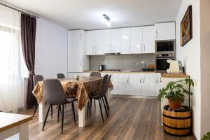 a kitchen with white cabinets and a table and chairs at CASA CODRILOR - Greencodru liniste si relaxare in Codru