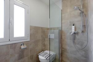 a bathroom with a toilet and a glass shower at Stay Easy Sidari Apartments in Sidari