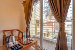 a room with a table and a large window at Itsy Hotels Snowdrop in Coimbatore