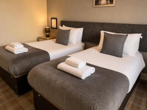 two beds in a hotel room with towels on them at The Anglers Inn in Guildtown +1 photo