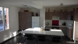eine Küche mit einem weißen Tisch und einem Kühlschrank in der Unterkunft Chez Tripp in Talmontiers