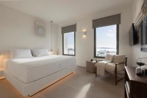 a white bedroom with a large bed and a chair at Celestial Villas in Santa Maria +34 photos