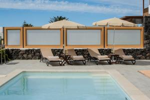 a pool with chairs and umbrellas on a patio at Villa Barrilla by Villalize in Tinajo +49 photos