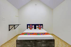 a white room with a bed with colorful pillows at FabHotel Mahi Resort in Aurangabad
