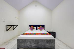 a white room with a bed with colorful pillows at FabHotel Mahi Resort in Aurangabad