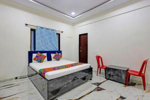 a bedroom with a bed and a red chair at FabHotel Mahi Resort in Aurangabad