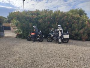 two people on motorcycles parked next to a bush at Villa delle Gazanie -Camera in villa -Vista panoramica sul Golfo in Quartu SantʼElena