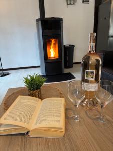 an open book on a table with glasses and a bottle of wine at Gîte au Bon Accueil Therence in Sainte-Thérence +22 photos