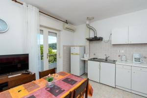 a kitchen and dining room with a table and a television at Apartments Verdea in Kampor