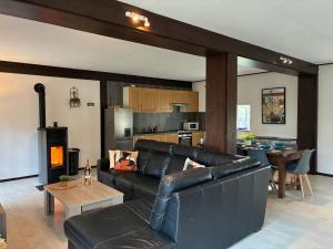 a living room with a black leather couch and a kitchen at Gîte au Bon Accueil Therence in Sainte-Thérence