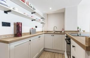 a kitchen with white cabinets and a sink at Chic City Apartment in Wakefield