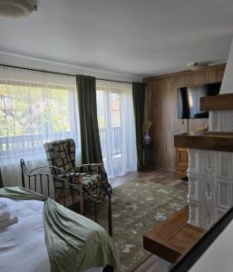 a room with a bed and a chair and a fireplace at DRUMUL DOMNISORILOR c in Buşteni