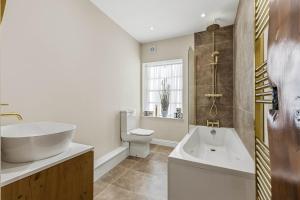 a bathroom with a tub and a sink and a toilet at Chic City Apartment in Wakefield +14 photos