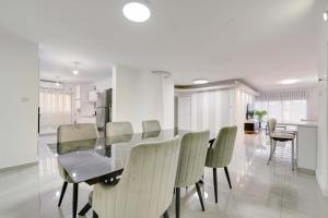 a dining room with a glass table and chairs at Spacious Luxury Beach Getaway by Torohome in Ashdod